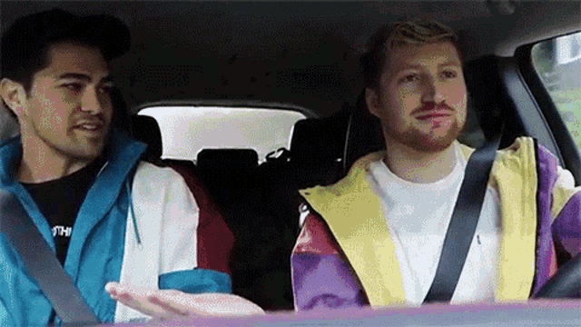 two men are sitting in a car and talking to each other .