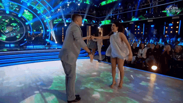 a man and a woman are dancing on a dance floor in front of a crowd that is watching dancing on ice
