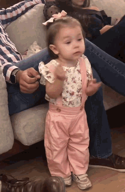 a little girl wearing pink overalls and a white top