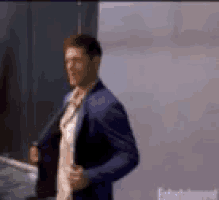 a man in a blue suit is standing in front of an entertainment sign