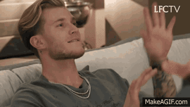 a man sitting on a couch giving a high five with makeagif.com in the corner