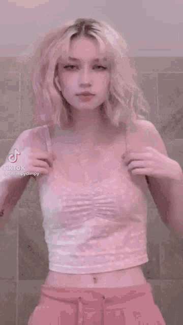 a woman with blonde hair is dancing in a pink tank top and pink shorts .