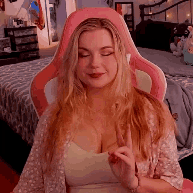 a woman is sitting in a pink chair in a bedroom .
