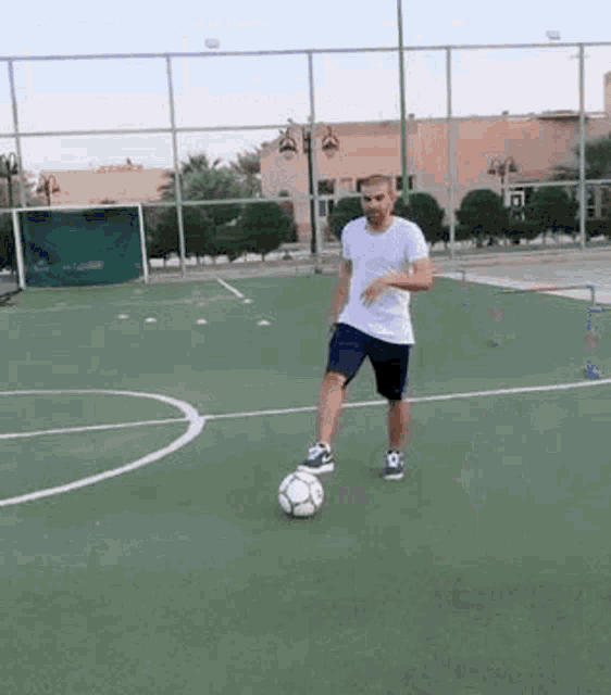 a man in a white shirt is kicking a soccer ball on a soccer field .