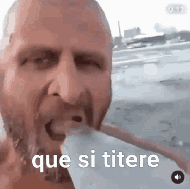 a man with a beard is drinking water from a bottle with the words que si titere written on it .