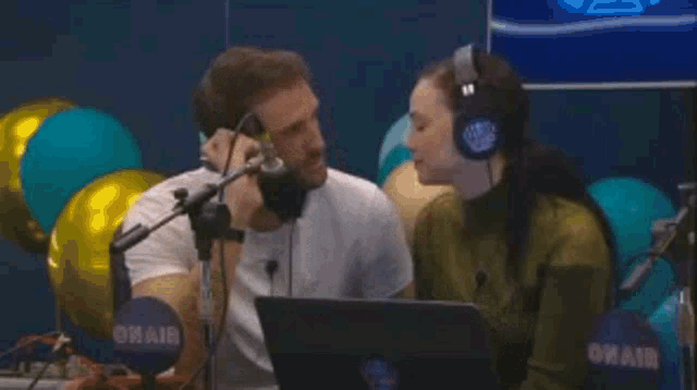 a man and a woman are kissing in front of a microphone and a sign that says sti caz * i .