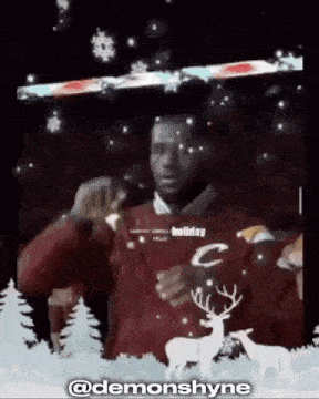 a man in a red sweater with deer on it is standing in front of a christmas scene .