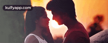 a man and a woman are kissing in front of the sun