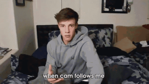 a young man sitting on a bed with the words " when cam follows me " on the bottom