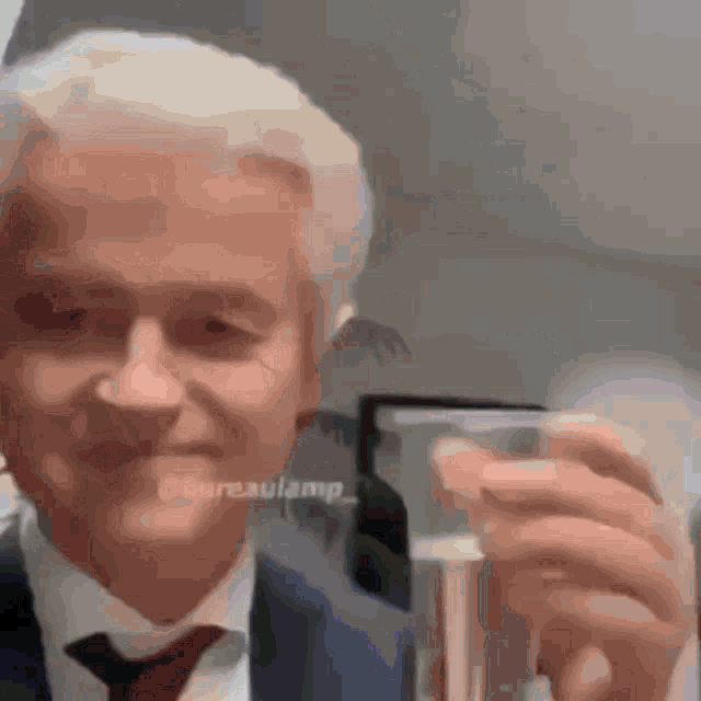 a man wearing a suit and tie is holding a glass of water