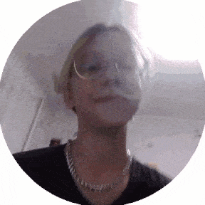 a woman wearing glasses and a chain around her neck looks at the camera