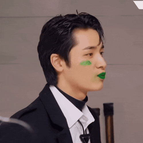 a man with green paint on his face is wearing a suit