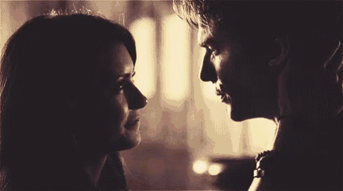 a man and a woman are looking into each other 's eyes and kissing .