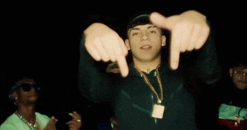 a young man is making a frame with his hands while wearing a necklace .