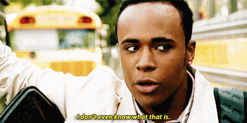 a young man is standing in front of a yellow school bus and talking .