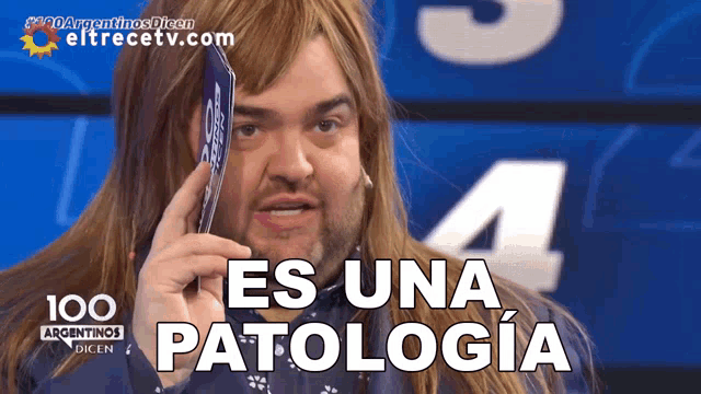a man with long hair is holding a card in front of his face and says " es una patologia "