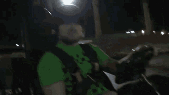 a man wearing a green shirt and a black hat is sitting in a car at night .