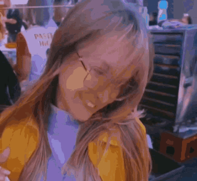 a woman wearing glasses and a yellow jacket is looking down