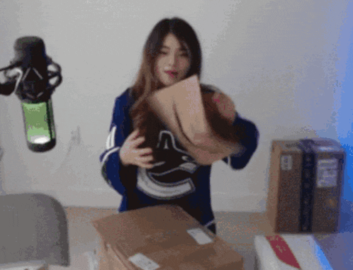 a woman in a blue vancouver canucks jersey is holding a cardboard box