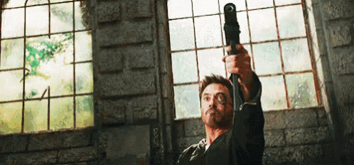 a man is pointing a gun at the camera in front of a window .