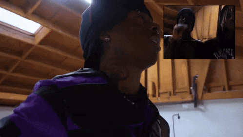 a man wearing a black hat and a purple shirt has the word night on his shirt