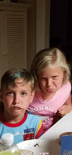 a boy wearing a shirt that says master makes a funny face next to a girl wearing a pink shirt that says zombie