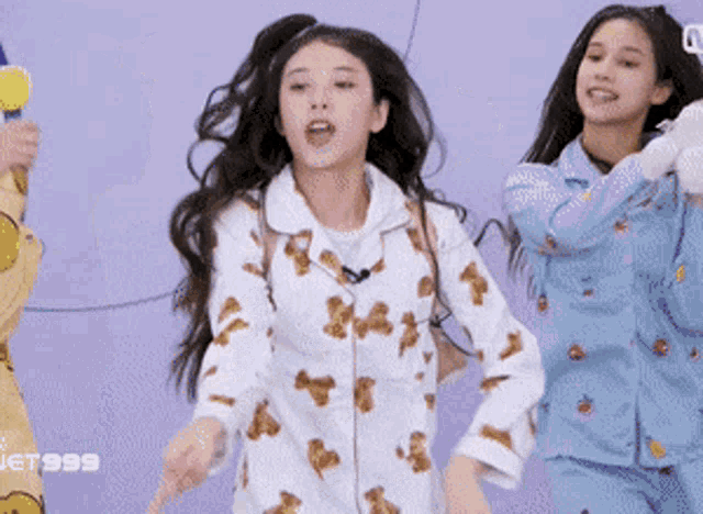 a girl in a teddy bear pajama is dancing with another girl