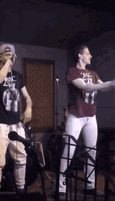 a man wearing a 2pac shirt stands next to a woman on stage