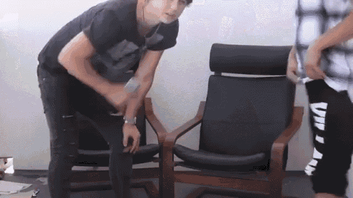 a man in a black shirt is standing next to a chair with the word villain on it .