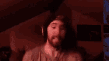 a man with a beard is covering his ears in a dark room