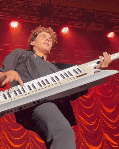 a young man is playing a keyboard on stage