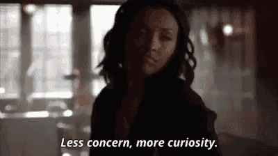 a woman is standing in a dark room and talking about less concern , more curiosity .