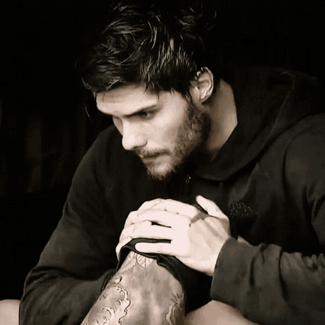 a man with a tattoo on his arm is wearing a black hoodie that says the north face