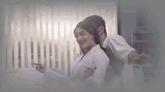 a man and a woman in lab coats are dancing together in a room .