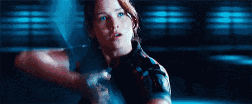 a woman is holding a gun in her hand and looking at the camera .