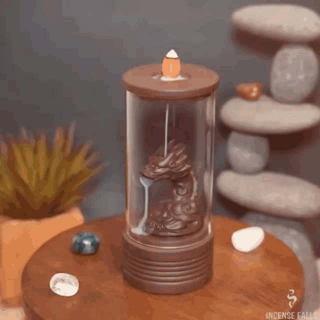 a dragon incense burner is sitting on a wooden table next to rocks .