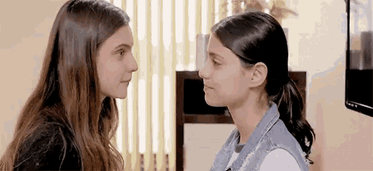 two women are looking at each other in a living room .