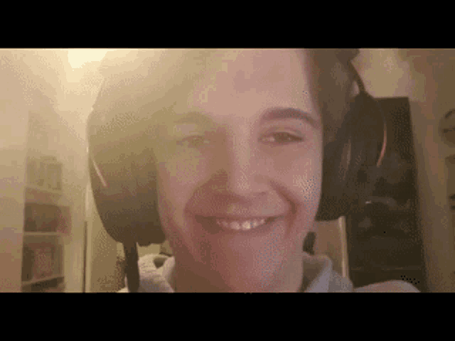 a young man wearing headphones smiles for the camera