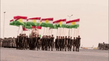 a group of soldiers marching in a parade holding flags .