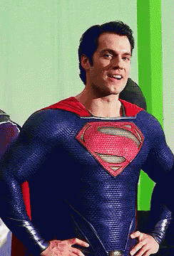 a man in a blue and red superman costume stands with his hands on his hips