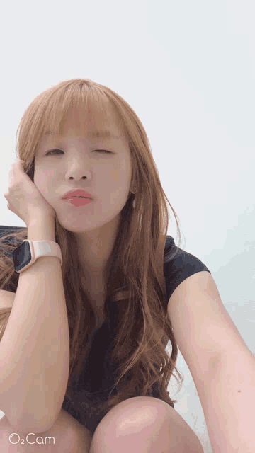 a woman taking a selfie with a watch on her wrist and the words o cam on the bottom right