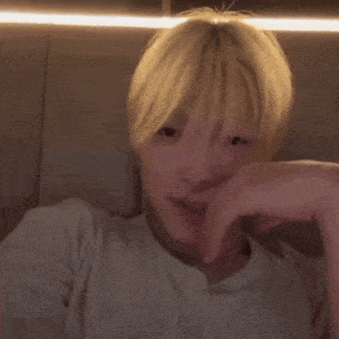 a man with blonde hair is sitting on a couch with his hand on his face