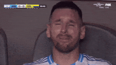 a soccer player covering his face with his hands while watching a game on fox