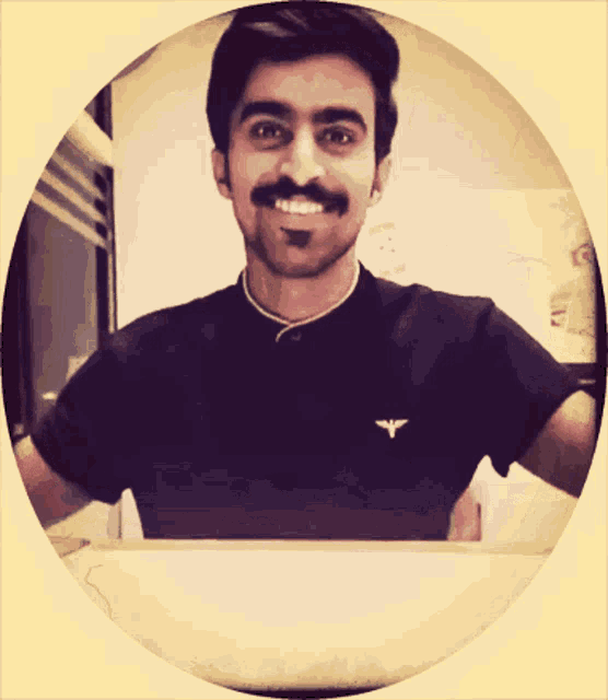 a man with a mustache is smiling and wearing a black shirt with an eagle on it