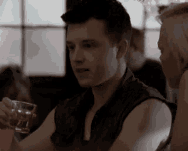 a man is sitting at a table with a glass of water in his hand