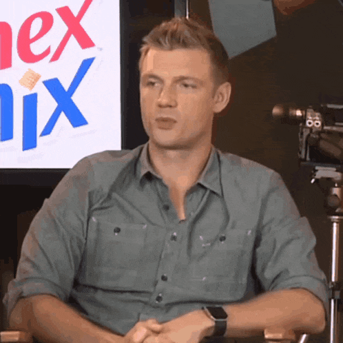 a man is sitting in front of a sign that says nix