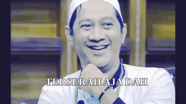 a man wearing a white hat is smiling with the words " terserah aja dah " behind him