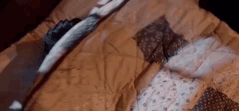 a person is laying on a bed with a blanket and a quilt .