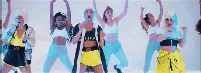 a group of women are dancing and one of them is wearing a black top with the letter m on it