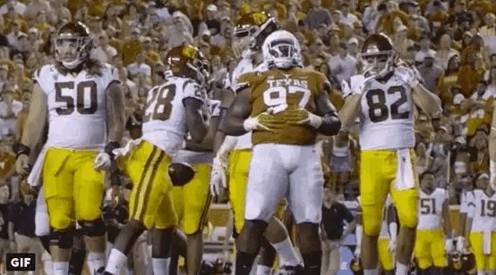 a group of football players in yellow uniforms are standing on the field .